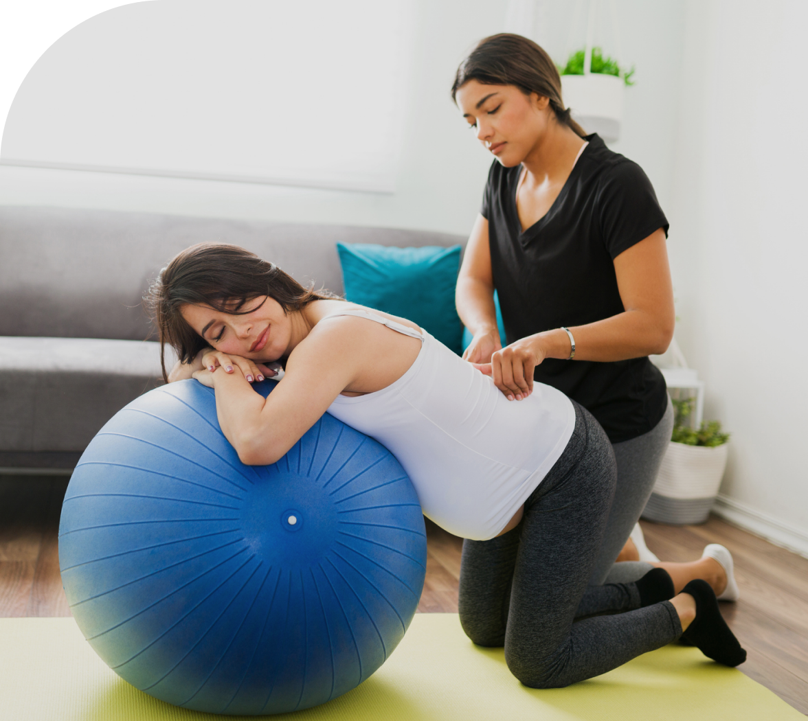 Pregnant woman leaning on exercise ball, assisted.